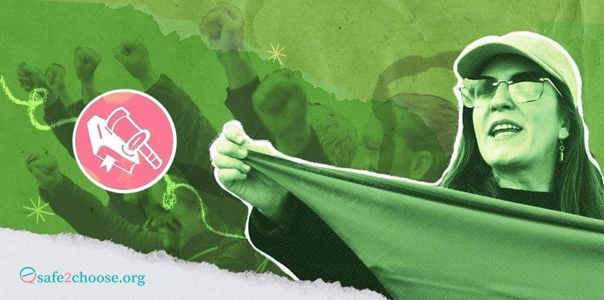Une femme tenant une banniere verte lors d une manifestation pro-choix, avec des poings leves en arriere-plan